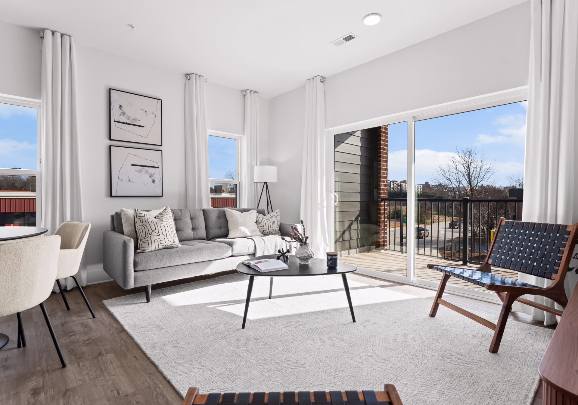 A one-bedroom living area with a grey sofa beside a sliding glass door onto the balcony.